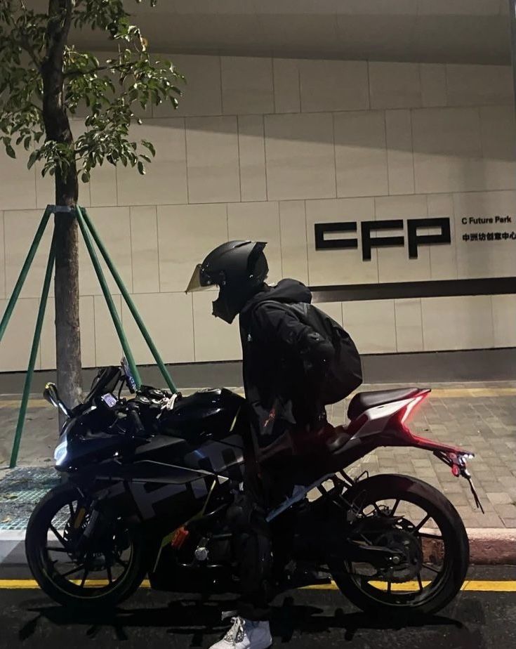 a person sitting on a motorcycle in front of a building