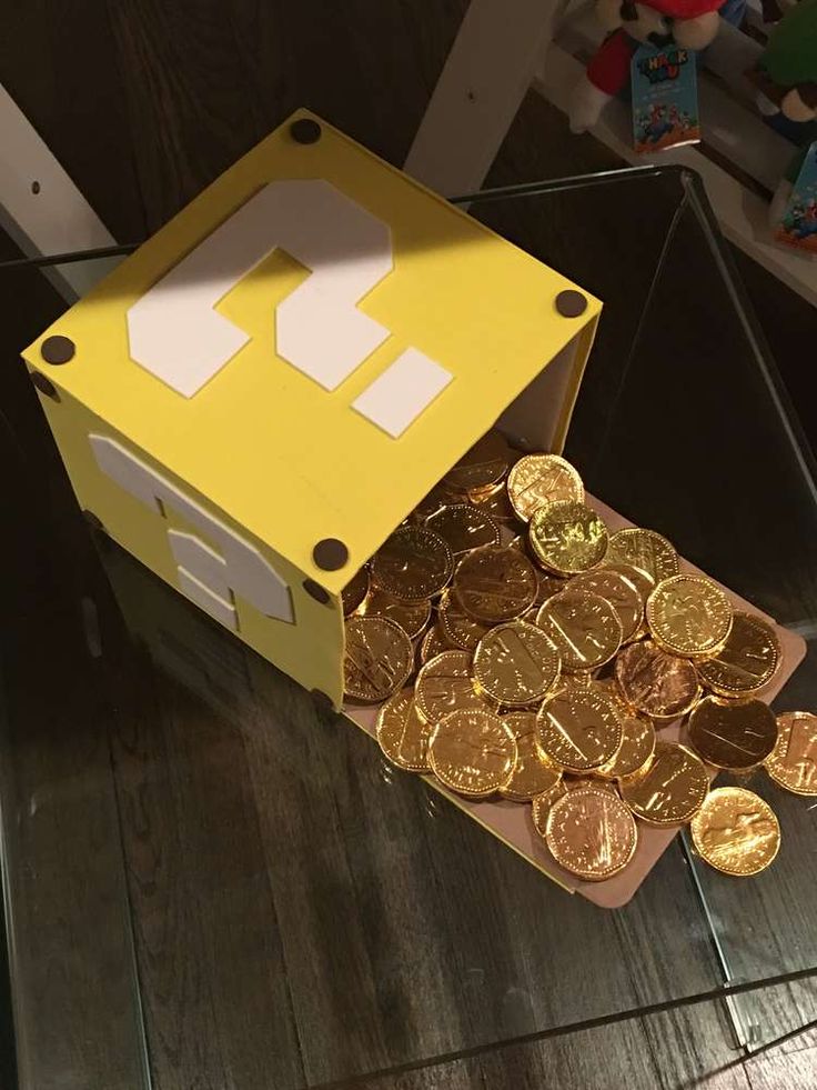 a box filled with gold coins sitting on top of a table next to a stuffed animal