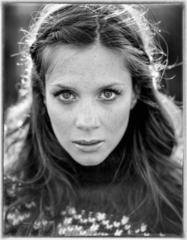 a black and white photo of a woman with freckles on her hair looking at the camera