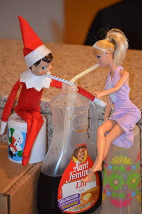 two elf dolls sitting on top of a counter next to an empty bottle and toothbrush