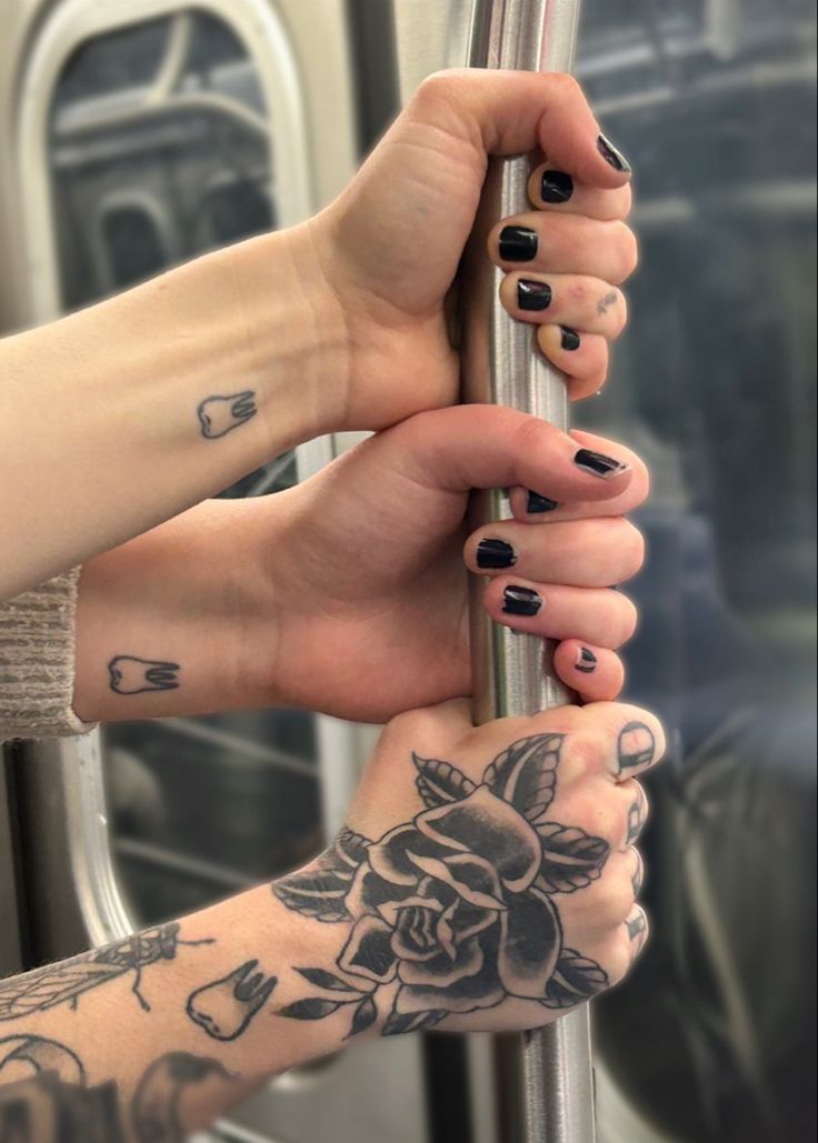 two people with tattoos on their hands are holding onto a pole and looking out the window