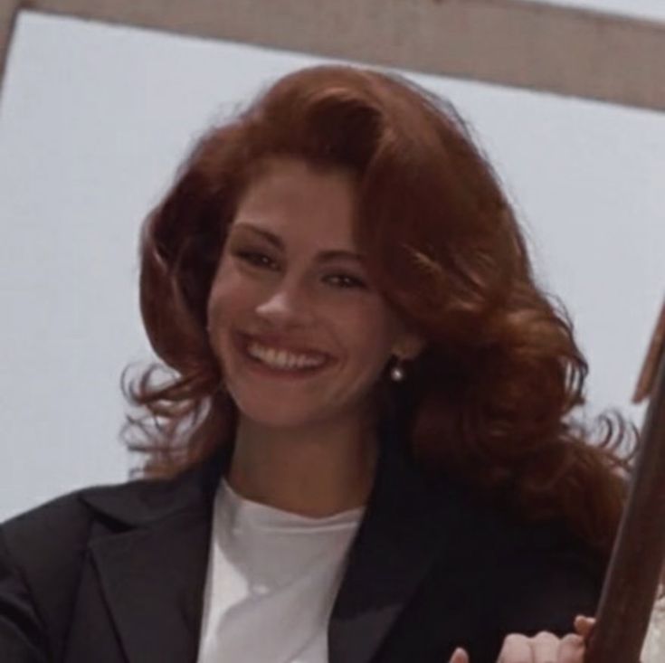 a woman with red hair is smiling and posing for the camera while wearing a black blazer