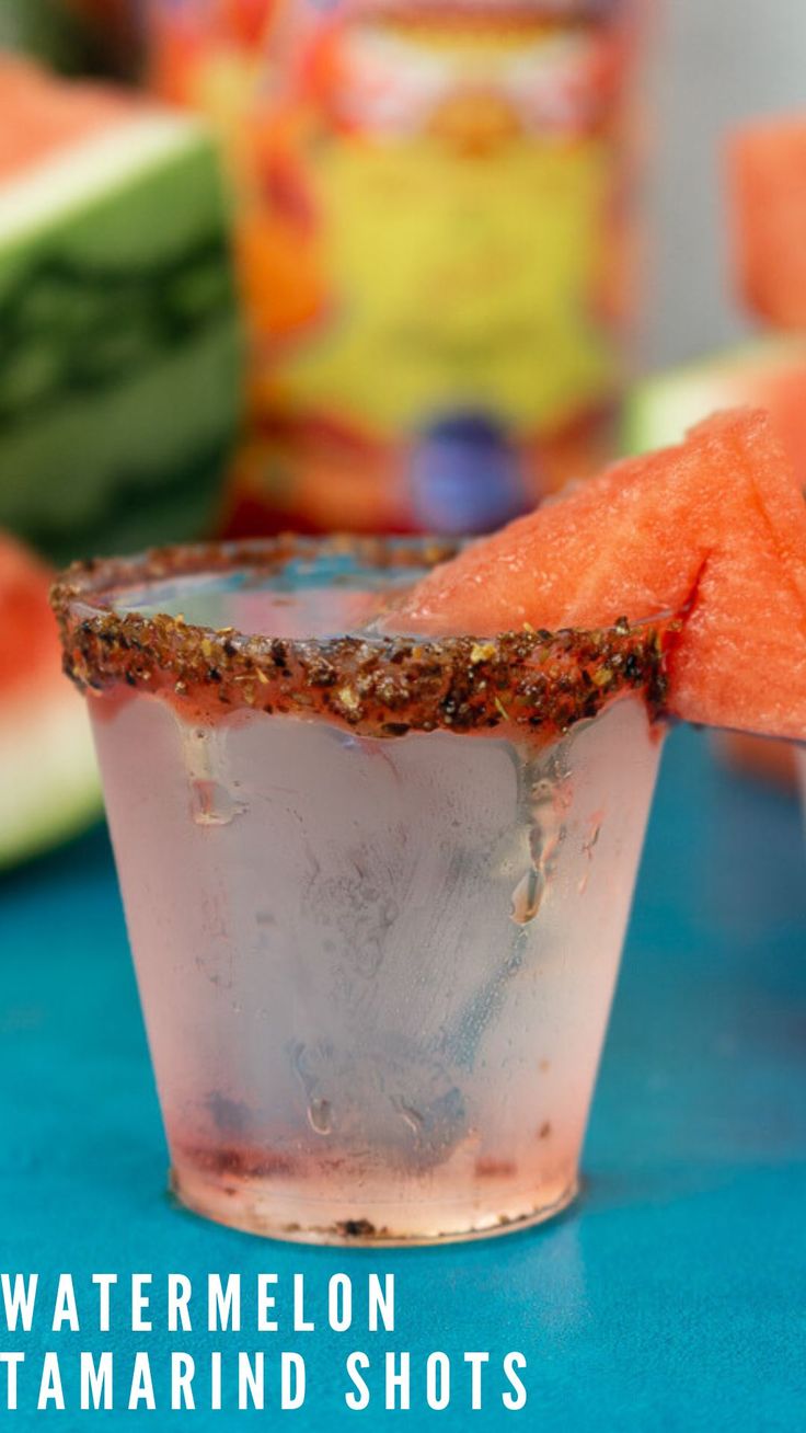 a watermelon margarita shot in a glass on a blue table