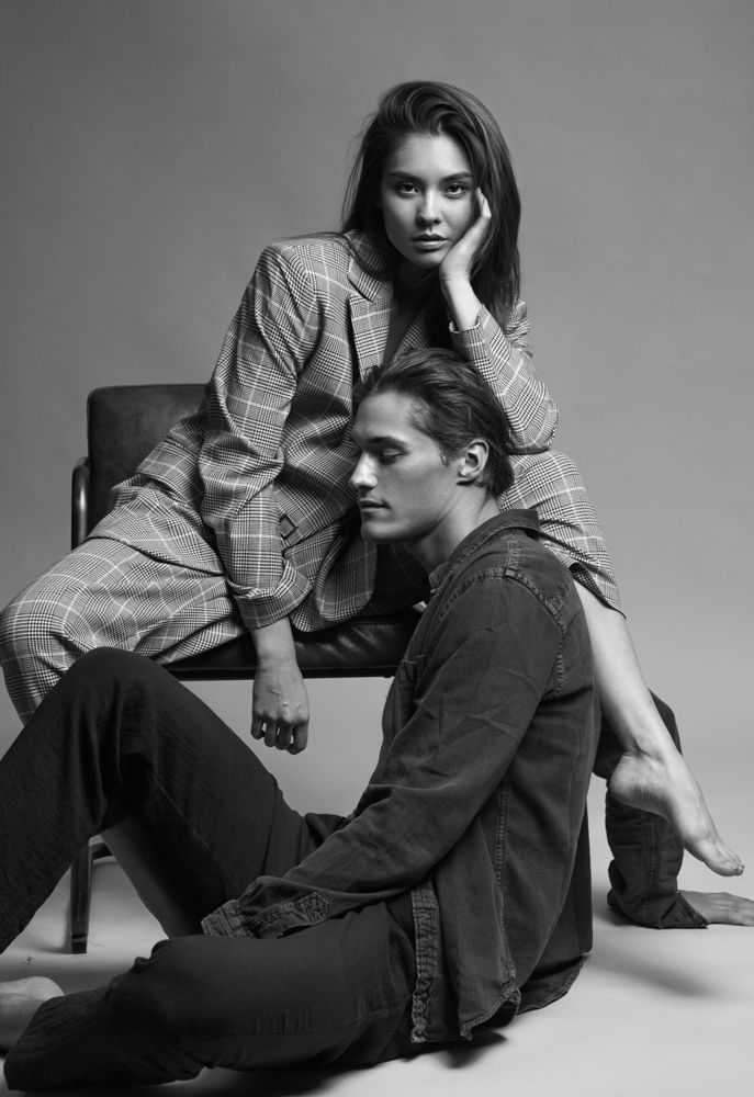 a man and woman sitting on top of a chair next to each other in black and white