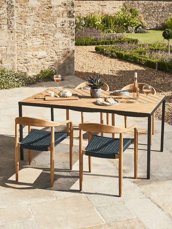 an outdoor table with two chairs and a potted plant in the middle is surrounded by stone walls