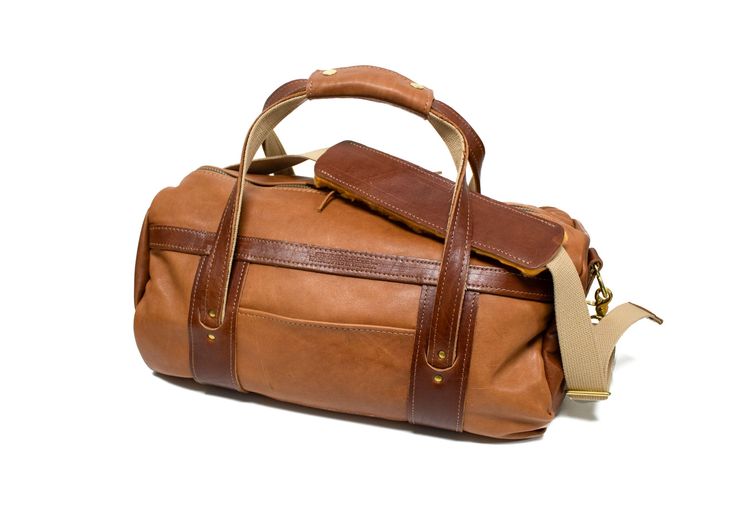 Natural Leather with Chestnut Leather Trim Made from hand-selected American tanned hides & American sourced brass hardware, our Steurer & Jacoby® Club Duffel Bags are perfect for going to the club, on a short get-away or on an outdoor adventure. Includes a free matching luggage tag ($25 value). Full Length Zipper Closure Deluxe Adjustable Sling Leather Handle Wrap Exterior Zippered Passport Pocket Easy Access Exterior Pocket Meets standard TSA Carry-on Regulations Measurements: 10”H x 8”D x 18”W Leather Shoulder Bag With Brass Hardware For Travel, Luxury Leather Satchel With Brass Hardware, Luxury Brown Satchel With Brass Hardware, Cognac Leather Travel Bag, Leather Weekender Bag In Cognac With Smooth Grain, Travel Bags With Bridle Leather And Leather Lining, Classic Cognac Duffle Bag With Leather Handles, Cognac Leather Weekender Bag With Smooth Grain, Cognac Duffle Bag With Leather Handles For Everyday Use