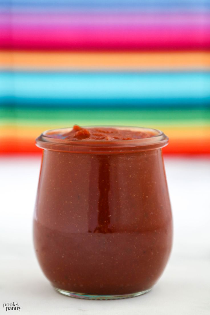 a glass jar filled with chocolate spread on top of a white tablecloth next to colorful striped wall