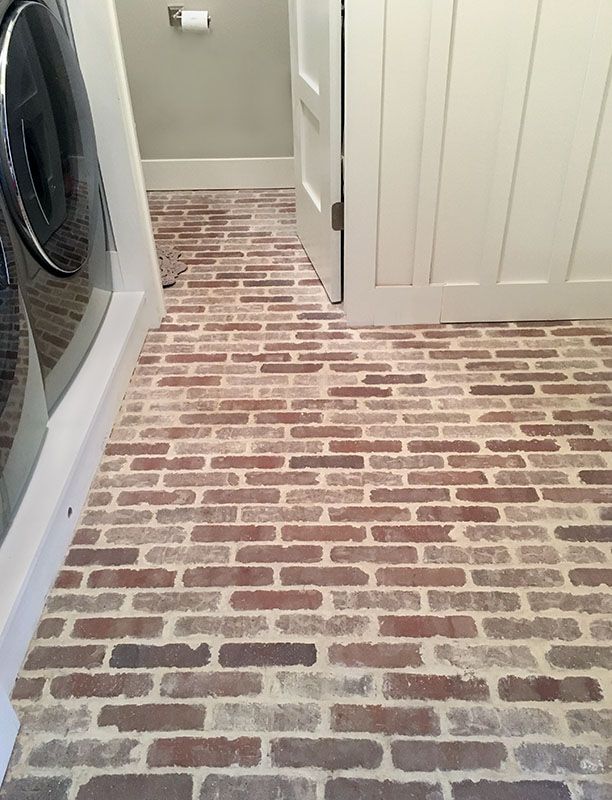 a washer and dryer sitting in a room next to a brick floor that has been painted white