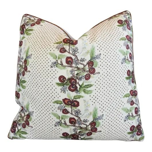 a white pillow with red flowers and polka dots on the front, sitting on a white background