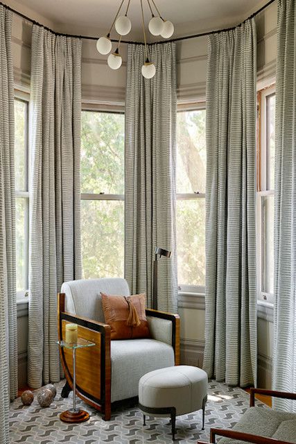 a living room filled with furniture and lots of window coverings on the windowsill