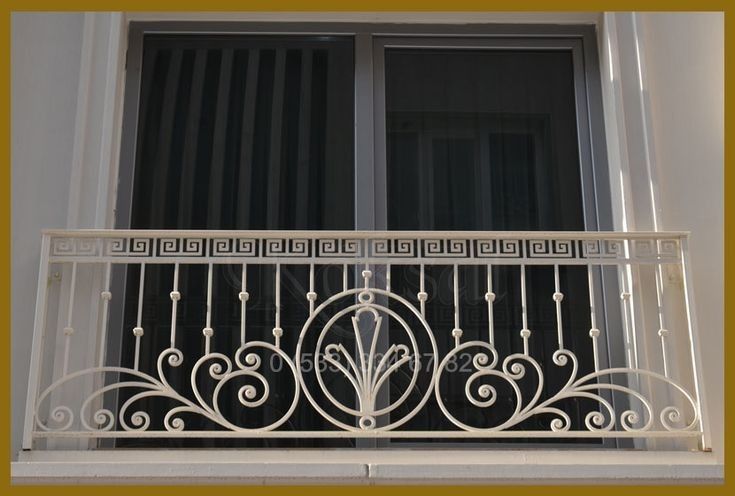 an iron balcony railing with decorative designs on the top and bottom, in front of a window