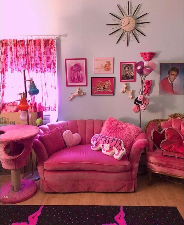 a living room with pink furniture and pictures on the wall