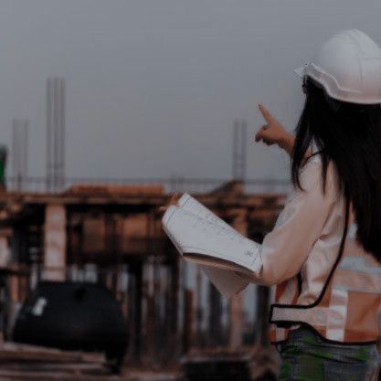 a woman wearing a hard hat and holding a book in her hand while standing on a construction site