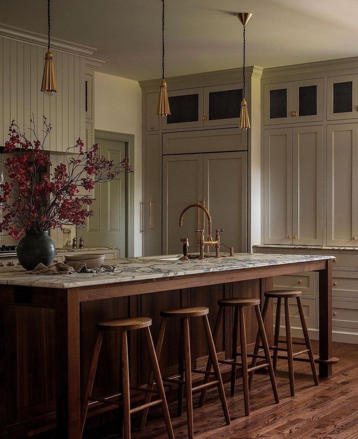 a kitchen island with three stools in front of it and flowers on the counter