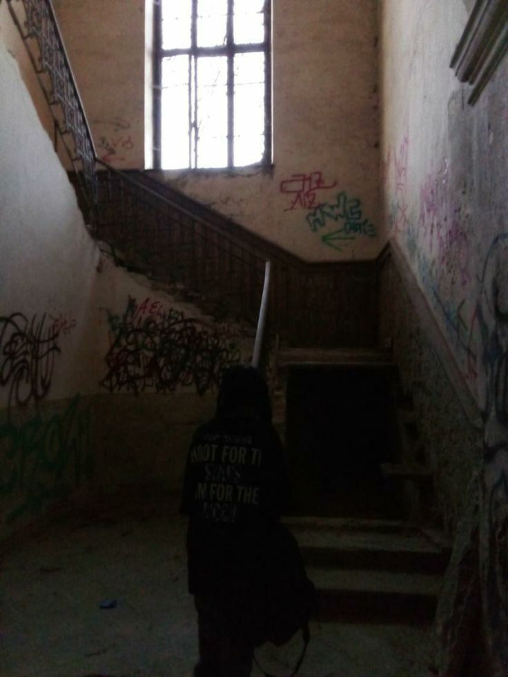 a person with a backpack is walking up the stairs in an old building that has graffiti all over it