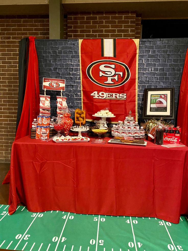 a table covered with food and snacks on top of a football field