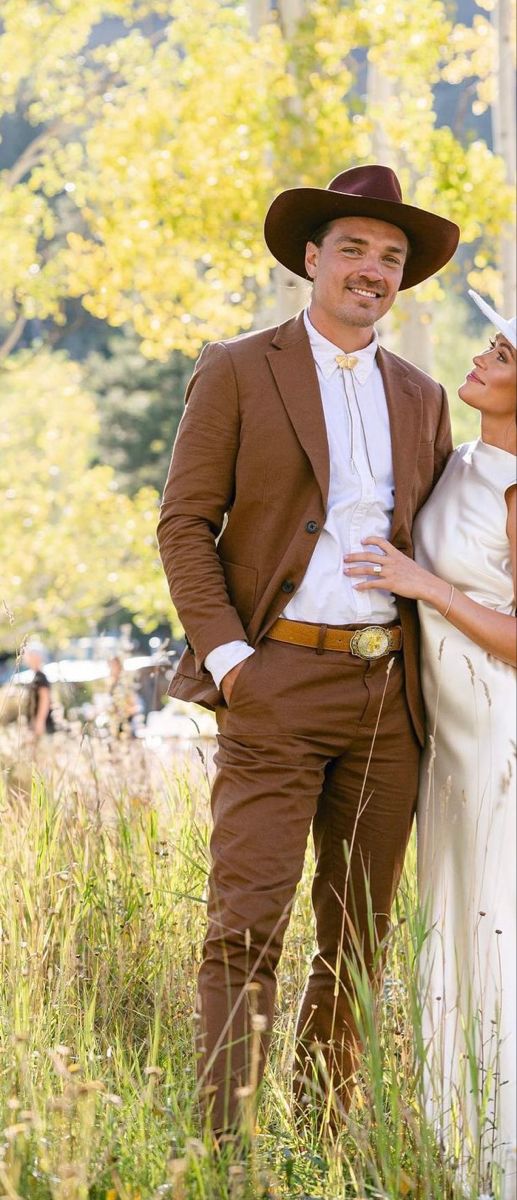 a man and woman standing next to each other in tall grass