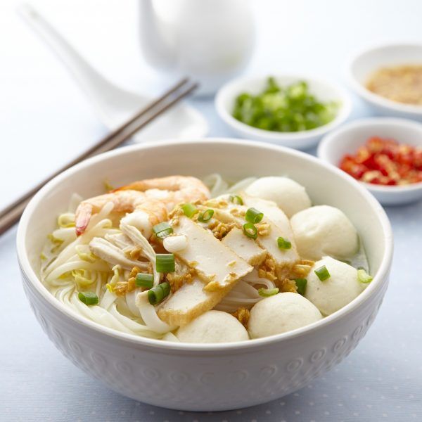 a white bowl filled with food next to chopsticks and bowls full of vegetables