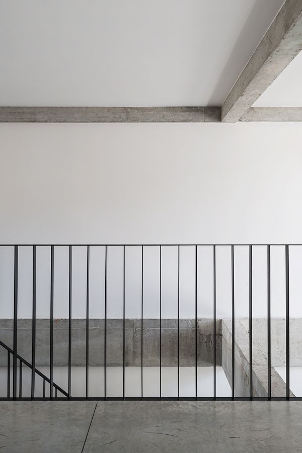 an empty room with metal railings and concrete flooring in front of a white wall