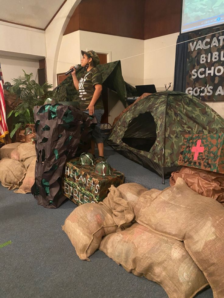 a man standing next to a pile of bags filled with stuff in front of a tent