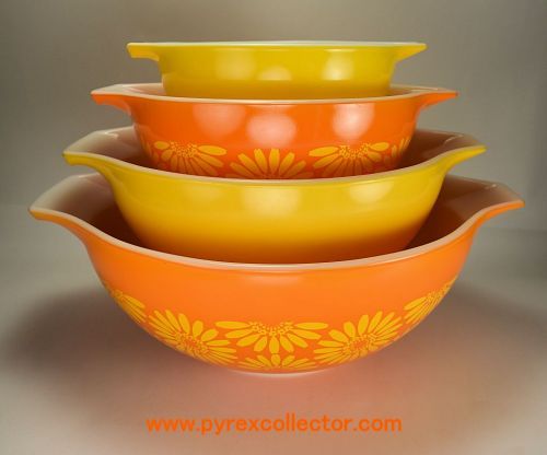 three yellow and orange bowls stacked on top of each other in front of a gray background