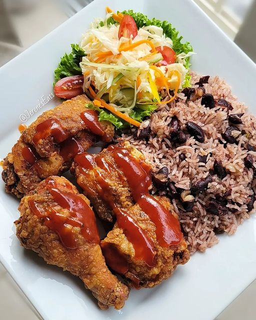 a white plate topped with rice and meat covered in bbq sauce next to coleslaw