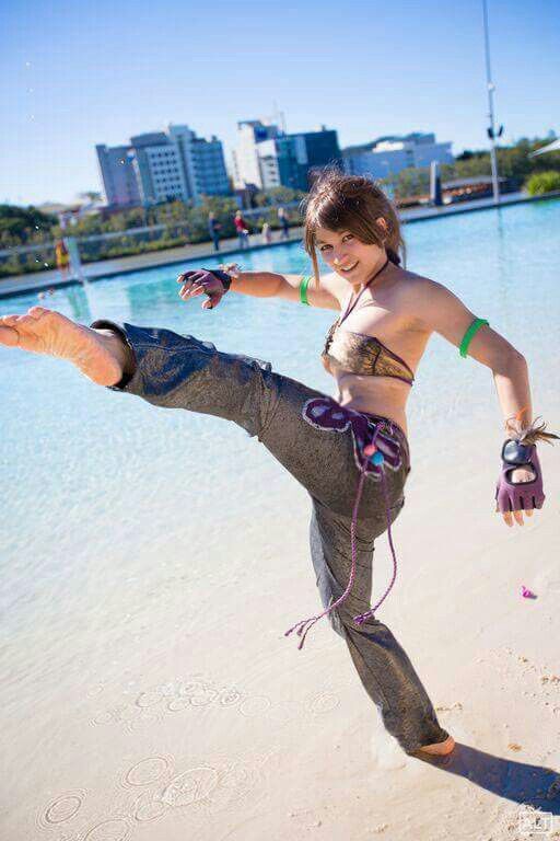 a woman is doing an acrobatic move on the beach