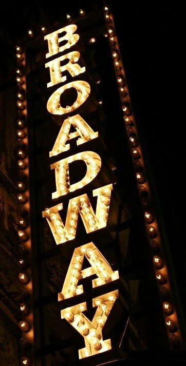 a sign that says broadway on it with lights all over the front and side of it