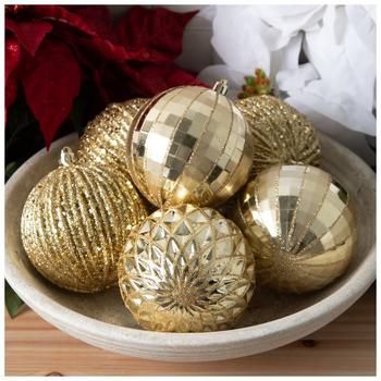 a bowl filled with shiny gold ornaments on top of a wooden table