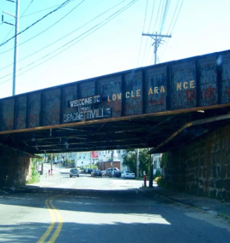 an old train bridge with graffiti on it over a street in the middle of town