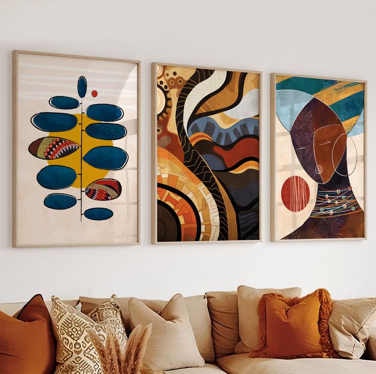 three abstract paintings hang on the wall above a couch in a living room with pillows