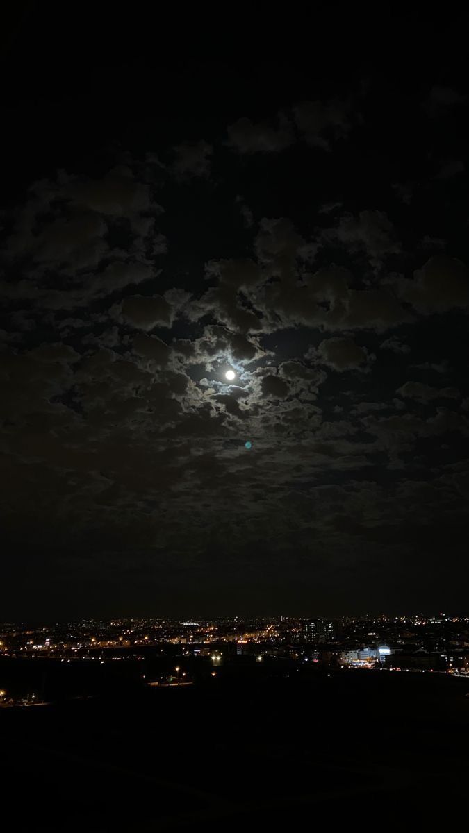 the moon is shining brightly in the night sky over a cityscape with buildings and trees