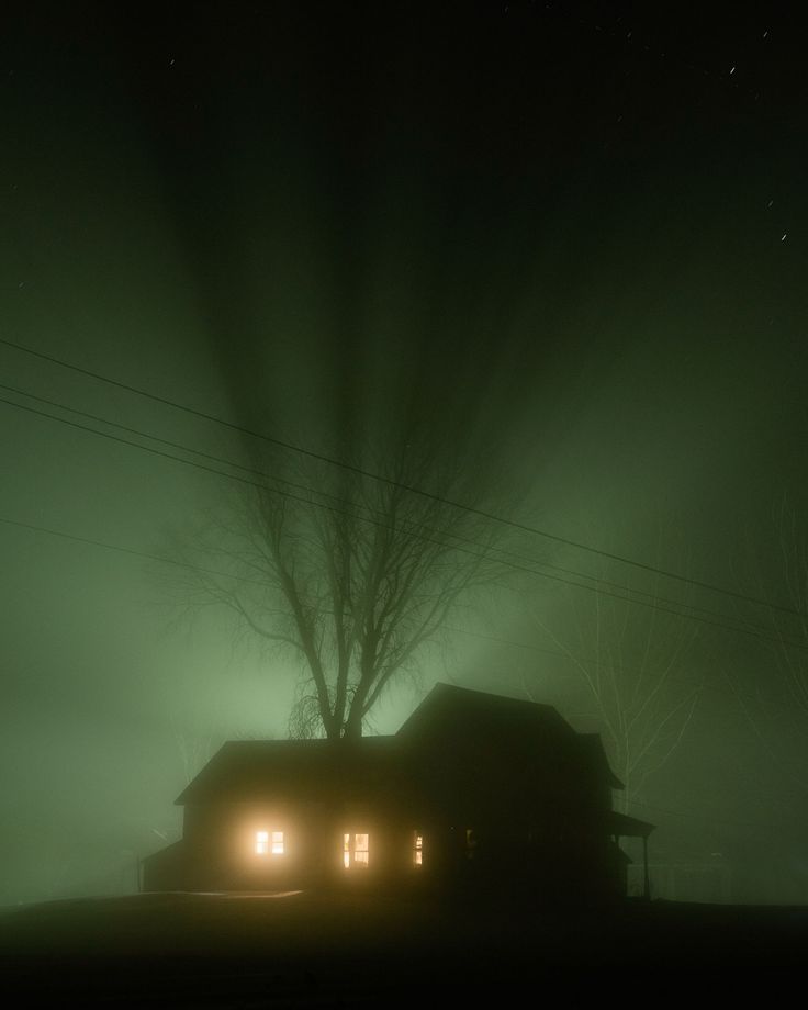 a house is lit up by headlights in the foggy night sky with trees and power lines