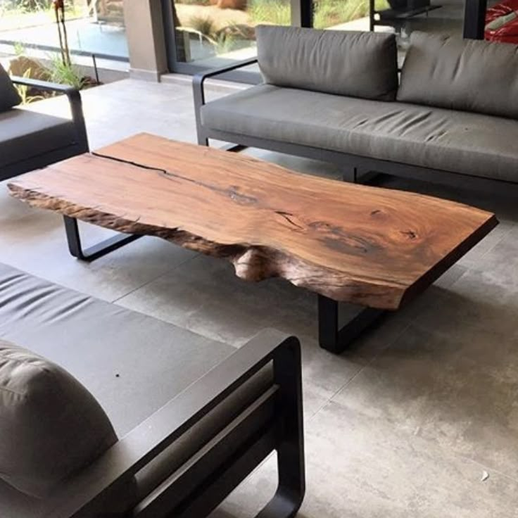 a wooden table sitting on top of a cement floor next to two gray couches