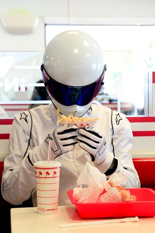 a person wearing a helmet sitting at a table with a drink and food in front of them