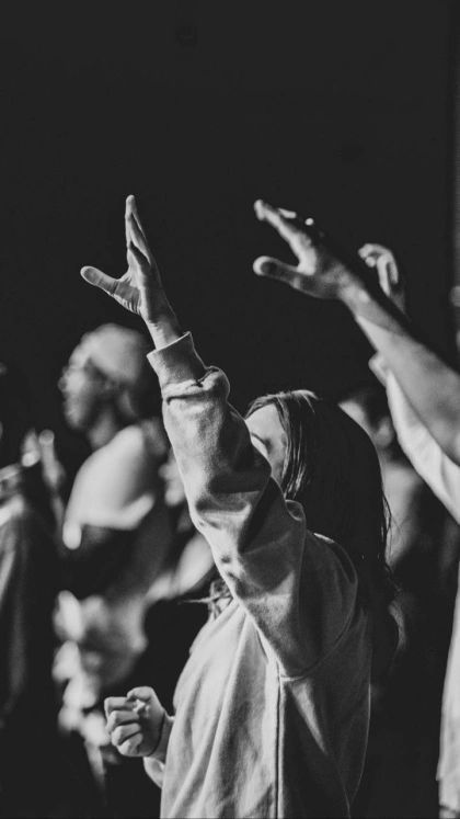 a group of people standing around each other with their hands in the air and one person reaching up