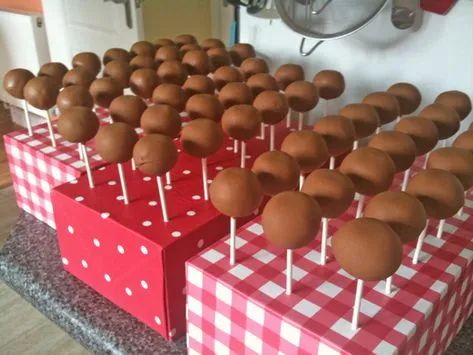 chocolate covered lollipops are lined up on red and white checkered boxes