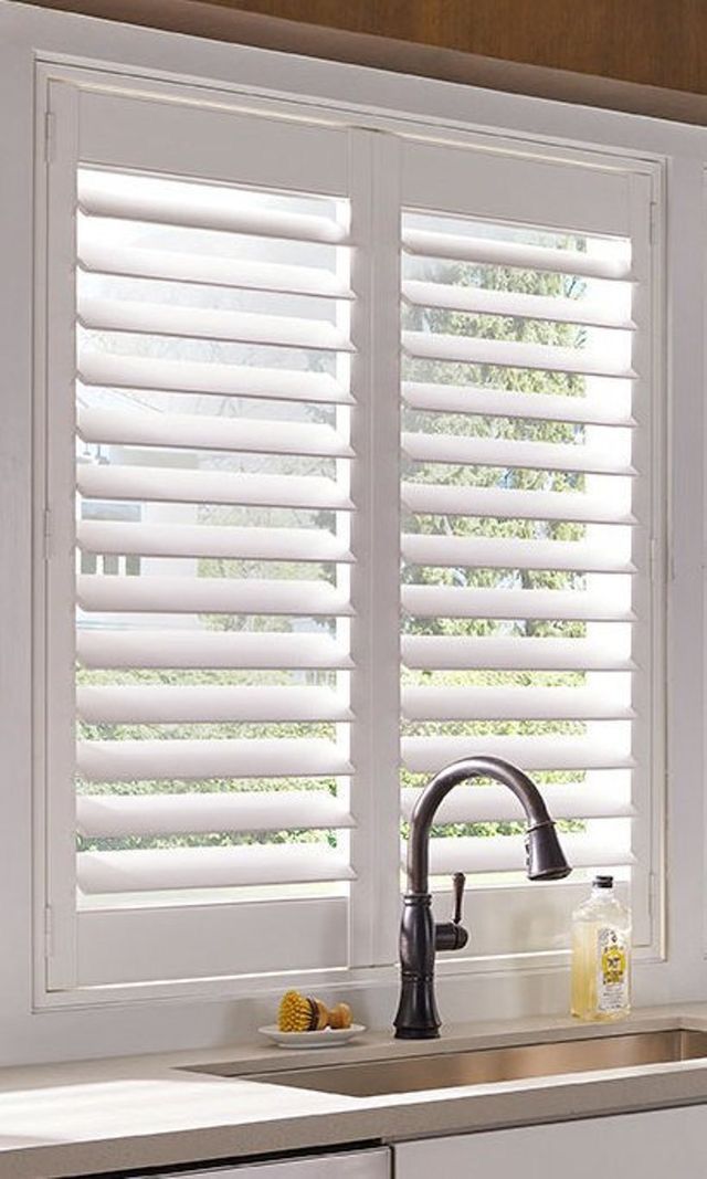 a kitchen with white shutters and sink