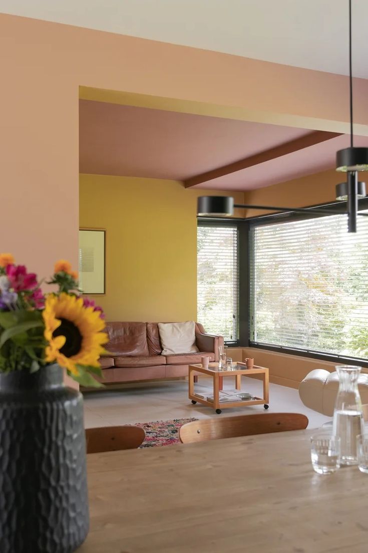 a living room filled with furniture and a wooden table topped with vases full of flowers