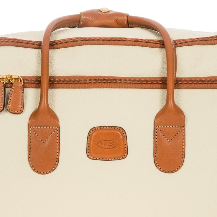 a tan and white suitcase with two brown tags on the handles, sitting against a white background