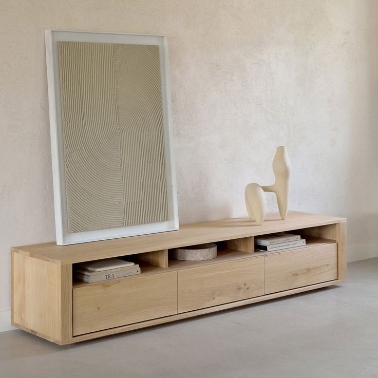 a large mirror sitting on top of a wooden shelf next to a vase and lamp