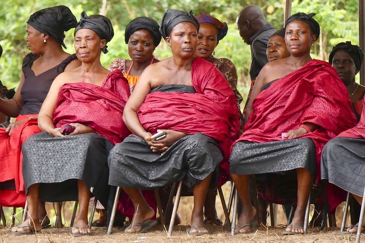 a group of women sitting next to each other wearing red cloths on their heads