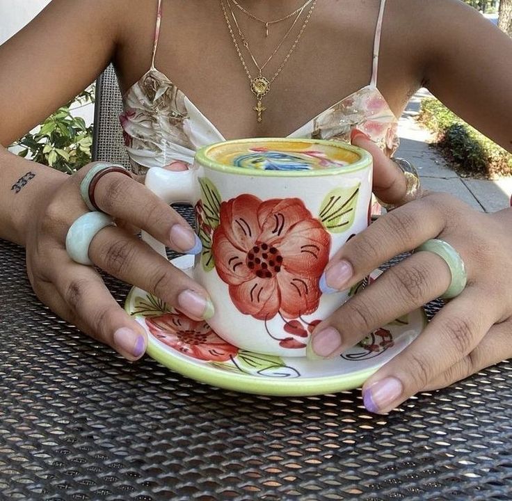 a woman sitting at a table holding a cup and saucer