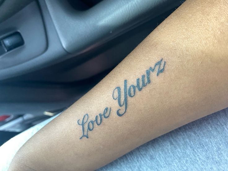 a person with a tattoo on their arm that says, love your's in cursive writing