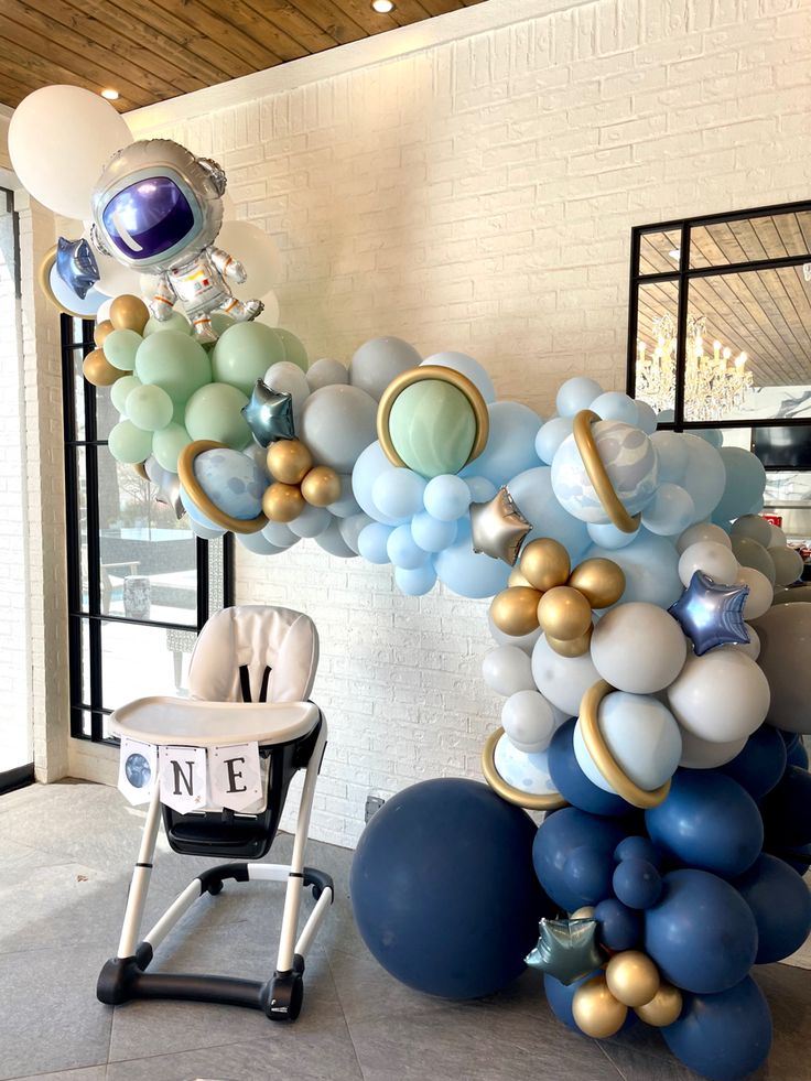 a balloon arch is decorated with blue, gold and white balloons