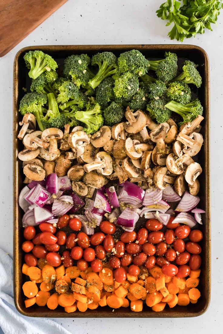 a tray filled with broccoli, tomatoes, mushrooms and other veggies