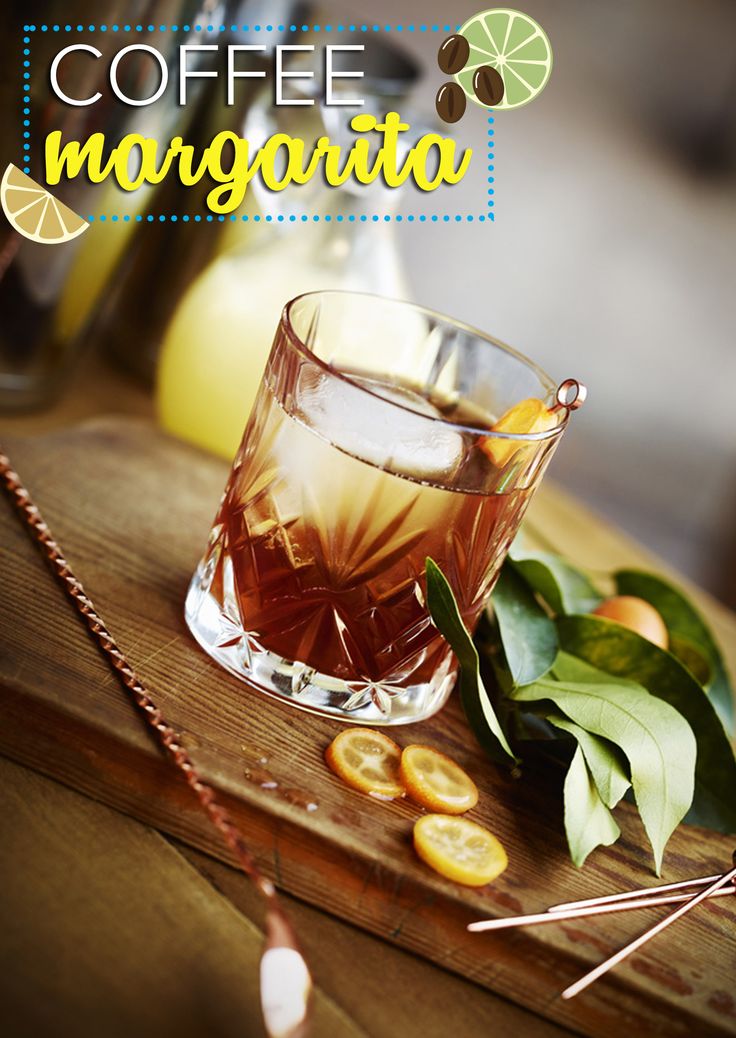 a glass filled with liquid sitting on top of a wooden table next to some orange slices