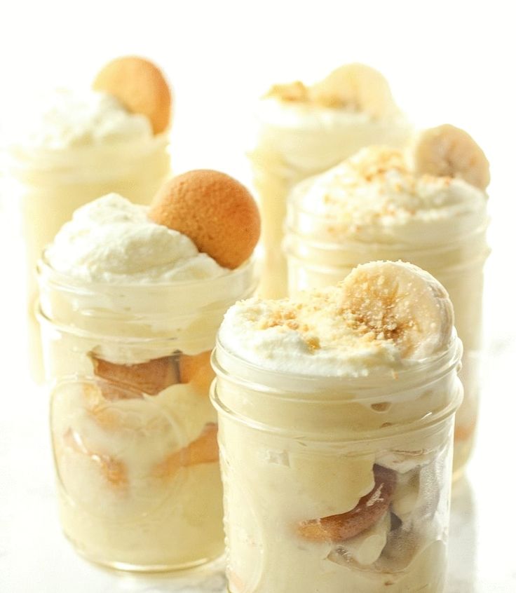 four jars filled with desserts sitting on top of a white countertop next to each other