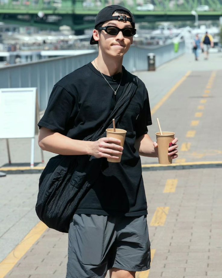 a young man is walking down the street with his coffee