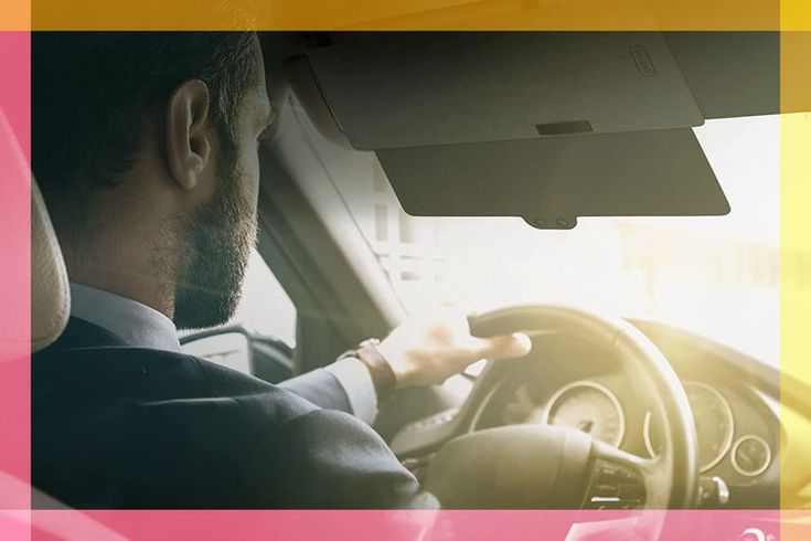 a man driving a car with the sun shining on his face and hands behind the steering wheel